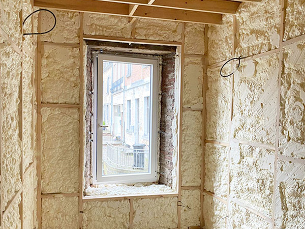 Isolation en mousse pulvérisée des murs intérieurs d'une petite pièce avec fenêtre extérieure