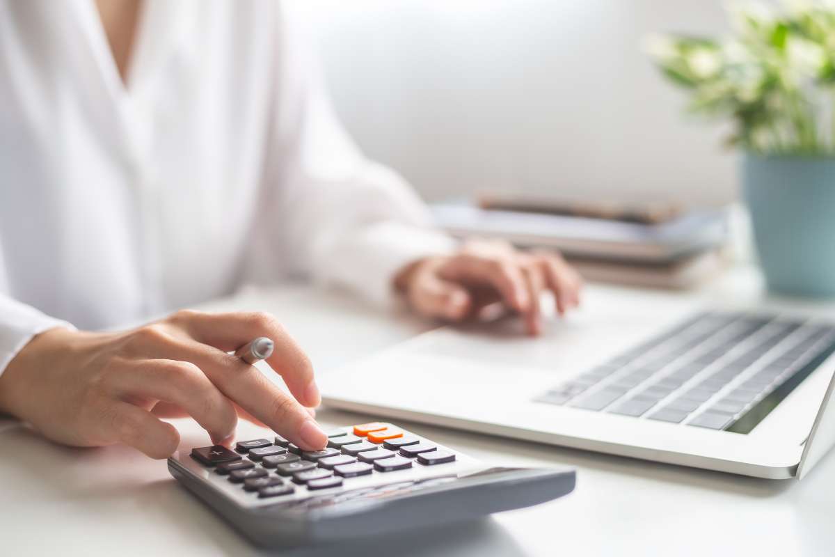 ISEO-credit-impot Femme assise à un bureau en train de calculer son crédit d'impôt pour l'isolation de sa toiture devant son ordinateur