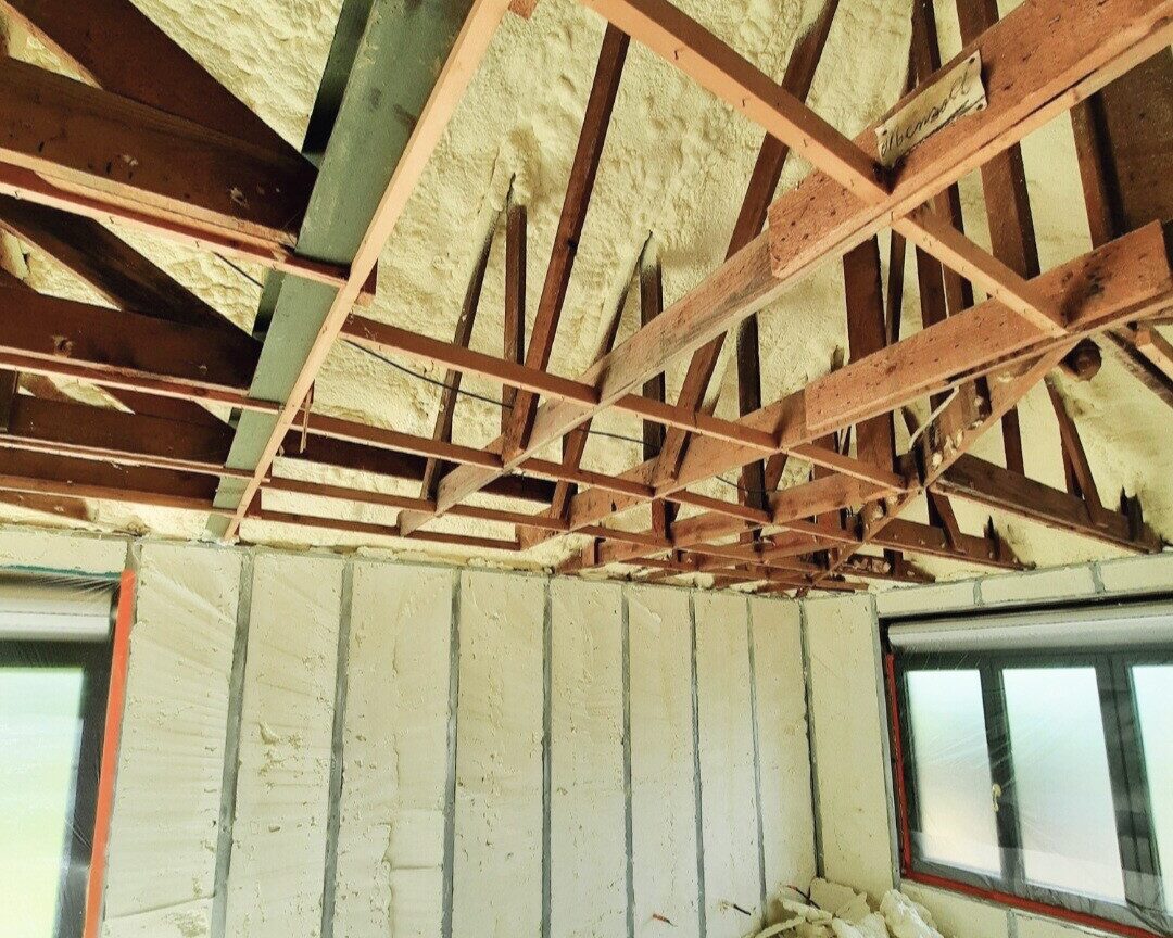 Intérieur d'une maison avec poutres en bois et mousse d'isolation projetée à l'intérieur