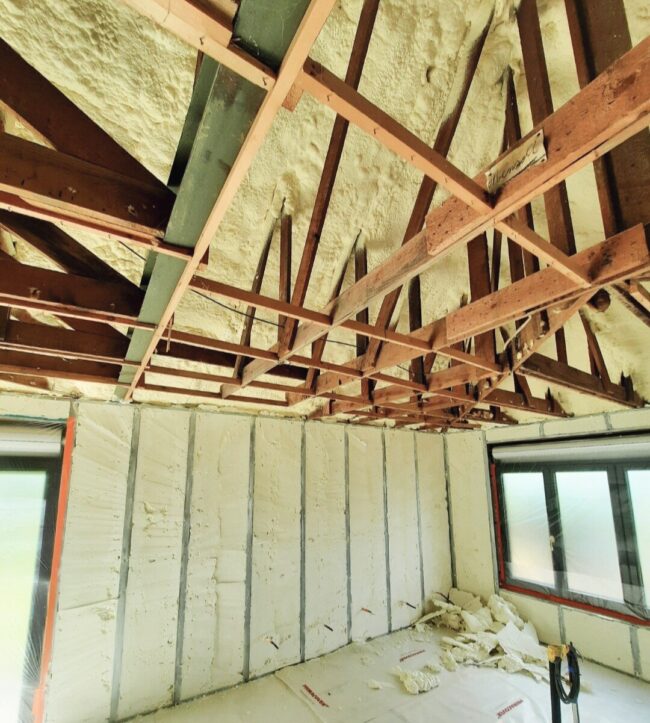 Intérieur d'une maison avec poutres en bois et mousse d'isolation projetée à l'intérieur