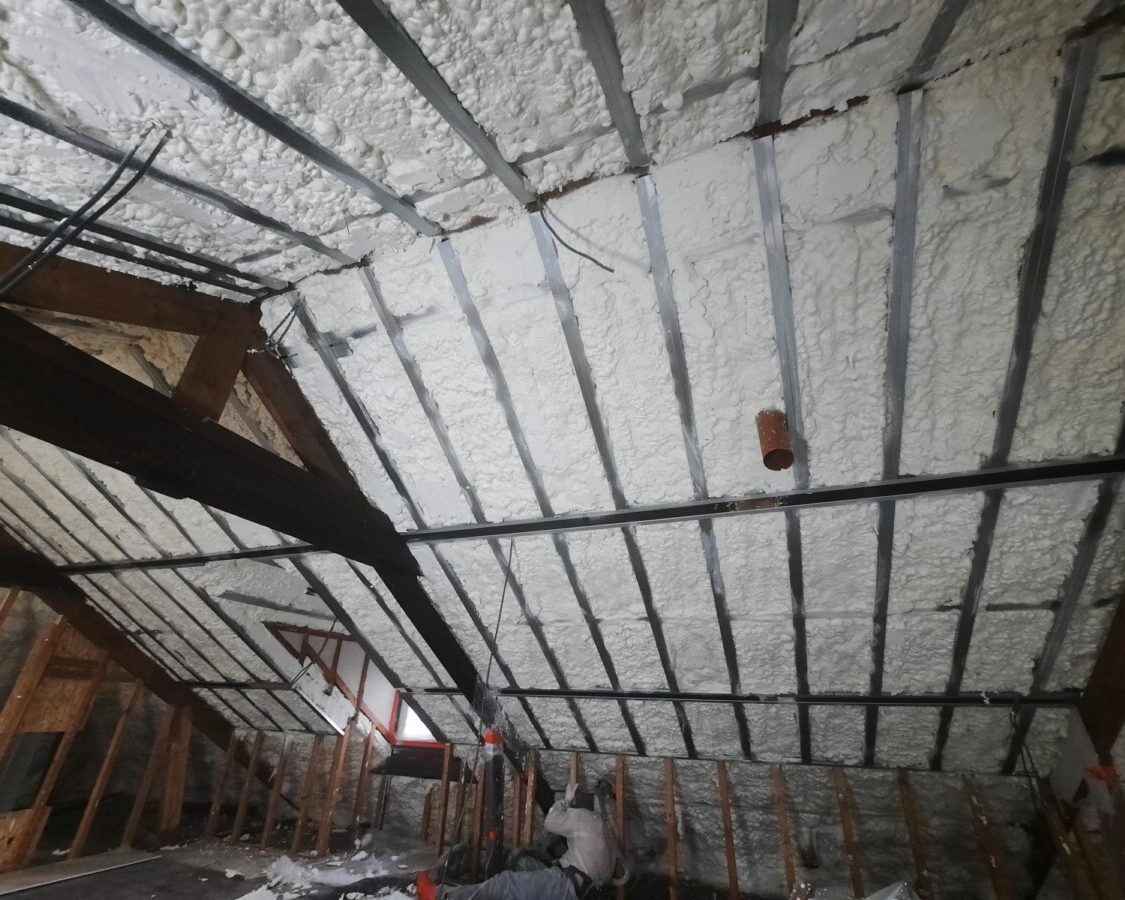 Chantier d'isolation d'une toiture de grenier avec vieille charpente en bois