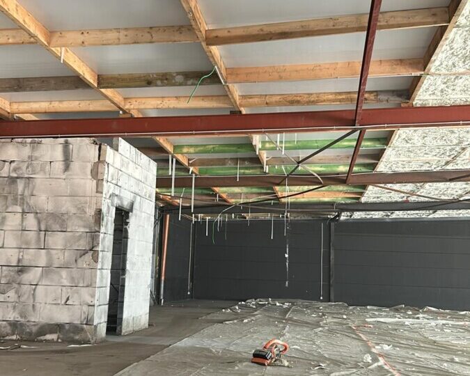 Travaux d'isolation du plafond d'un magasin à La Louvière, avec préparation de la structure avant application de la mousse isolante.