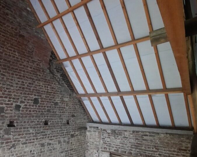 Vue intérieure de la toiture d'une grange à Affligem, avant application de l'isolation, montrant les chevrons et la préparation pour l'isolation thermique.
