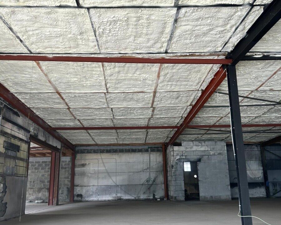 Isolation en mousse polyuréthane sur le plafond d'un showroom à La Louvière, montrant la couverture complète pour une isolation optimale.