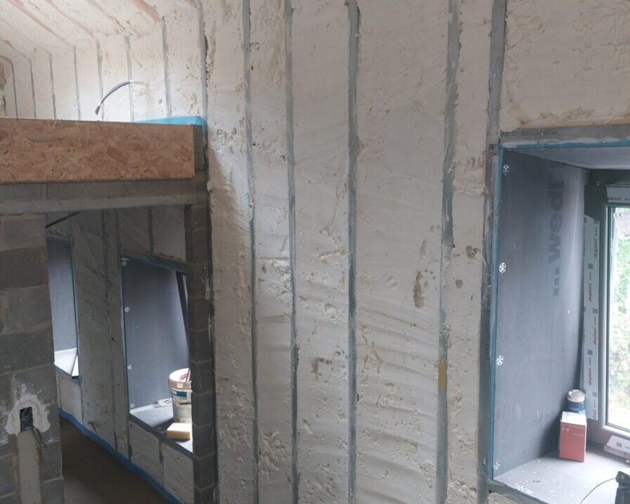 Vue intérieure d'une maison ancienne à Grand-Rechain avec mousse isolante projetée sur les murs et le plafond sous les chevrons en bois."