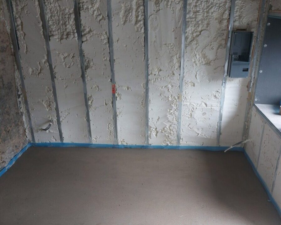 Mur isolé de l'intérieur avec mousse polyuréthane projetée dans une pièce rénovée d'une maison ancienne.