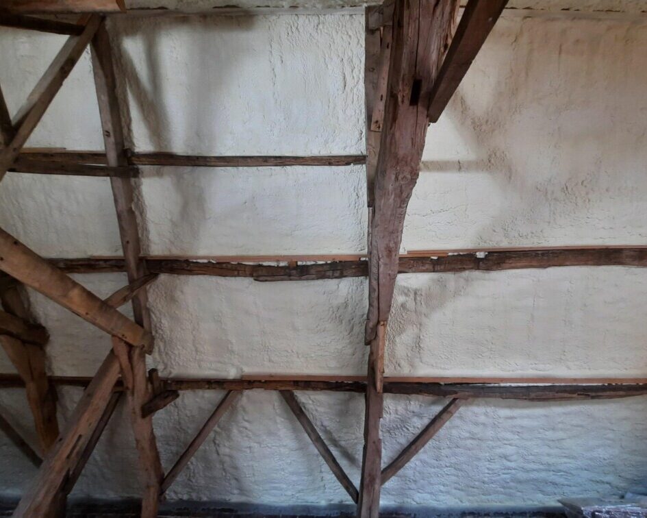 Vue d'ensemble de l'isolation thermique en mousse projetée sous le toit d'une grange à Affligem, montrant la finition des travaux.