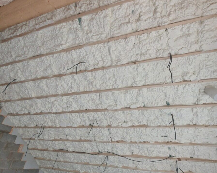 Plafond isolé avec mousse projetée et chevrons apparents dans une pièce de ferme rénovée.