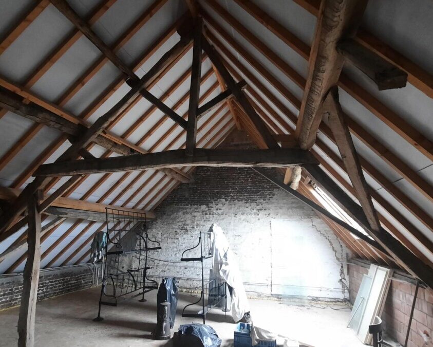 Charpente traditionnelle d'une grange à Affligem avec isolation en mousse polyuréthane projetée, dans le cadre d'une rénovation énergétique.