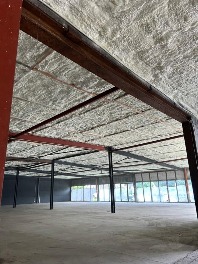 Plafond isolé avec mousse à cellules ouvertes dans un magasin en rénovation à La Louvière avec de la structure en métal supportant l'isolation.