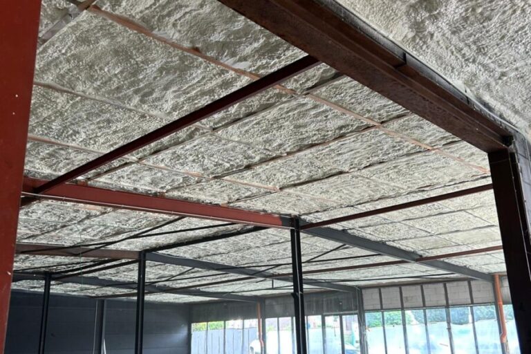 Plafond isolé avec mousse à cellules ouvertes dans un magasin en rénovation à La Louvière avec de la structure en métal supportant l'isolation.