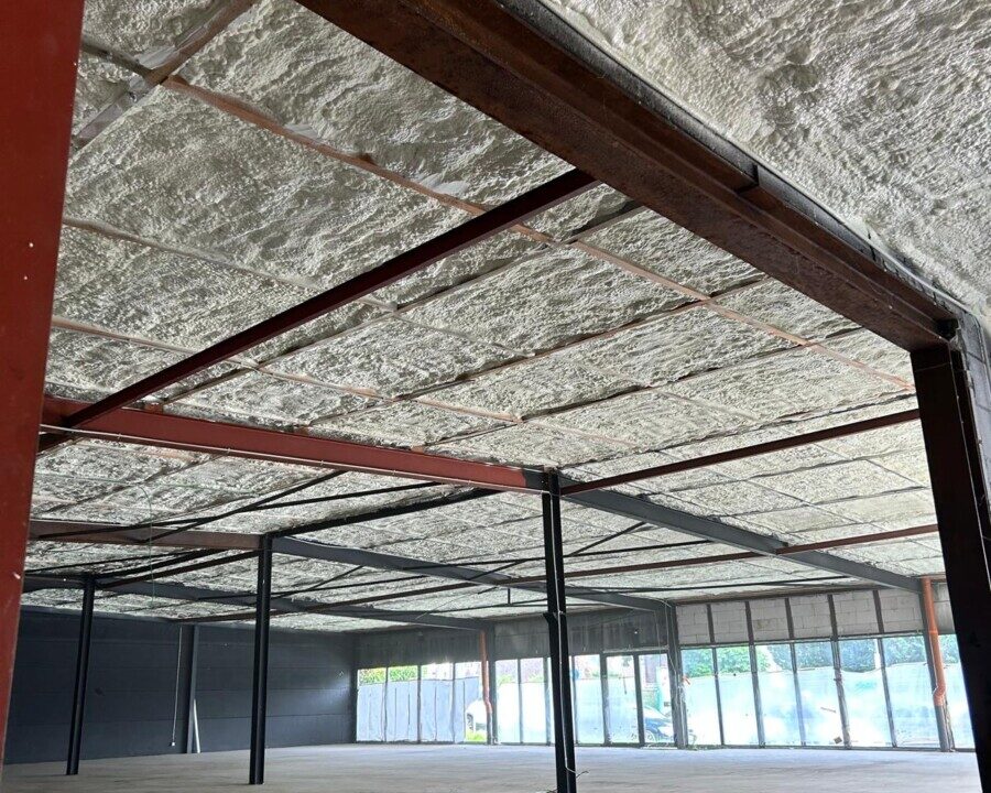 Plafond isolé avec mousse à cellules ouvertes dans un magasin en rénovation à La Louvière avec de la structure en métal supportant l'isolation.