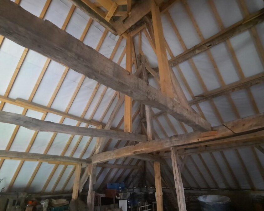 Intérieur d'une grange à Affligem avec isolation de toiture en mousse, visant à améliorer l'isolation thermique.