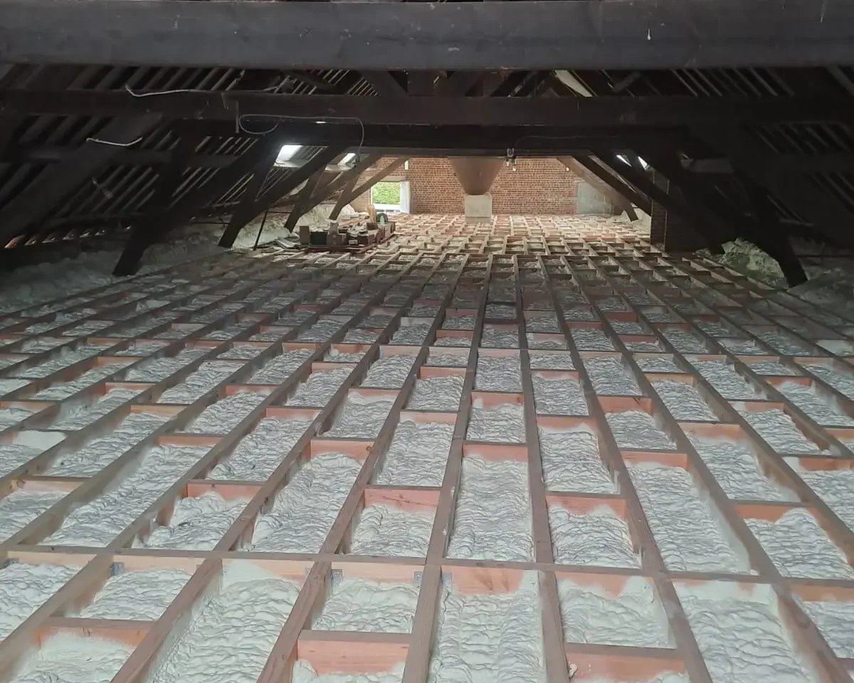 Plancher de grenier isolé à Destelbergen, avec de la mousse ICYNENE LITE+ appliquée entre les poutres en bois pour une isolation thermique et acoustique optimale.