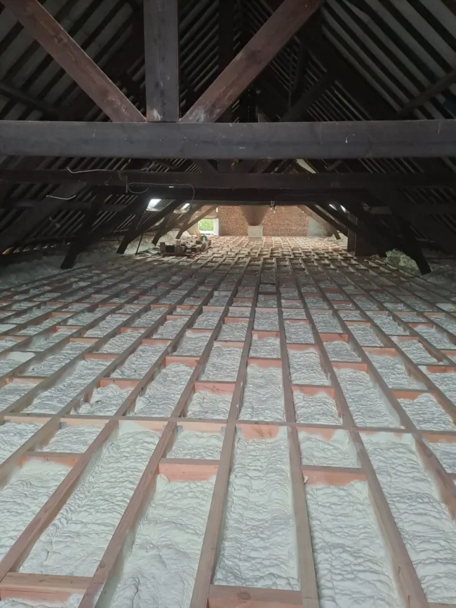 Plancher de grenier isolé à Destelbergen, avec de la mousse ICYNENE LITE+ appliquée entre les poutres en bois pour une isolation thermique et acoustique optimale.