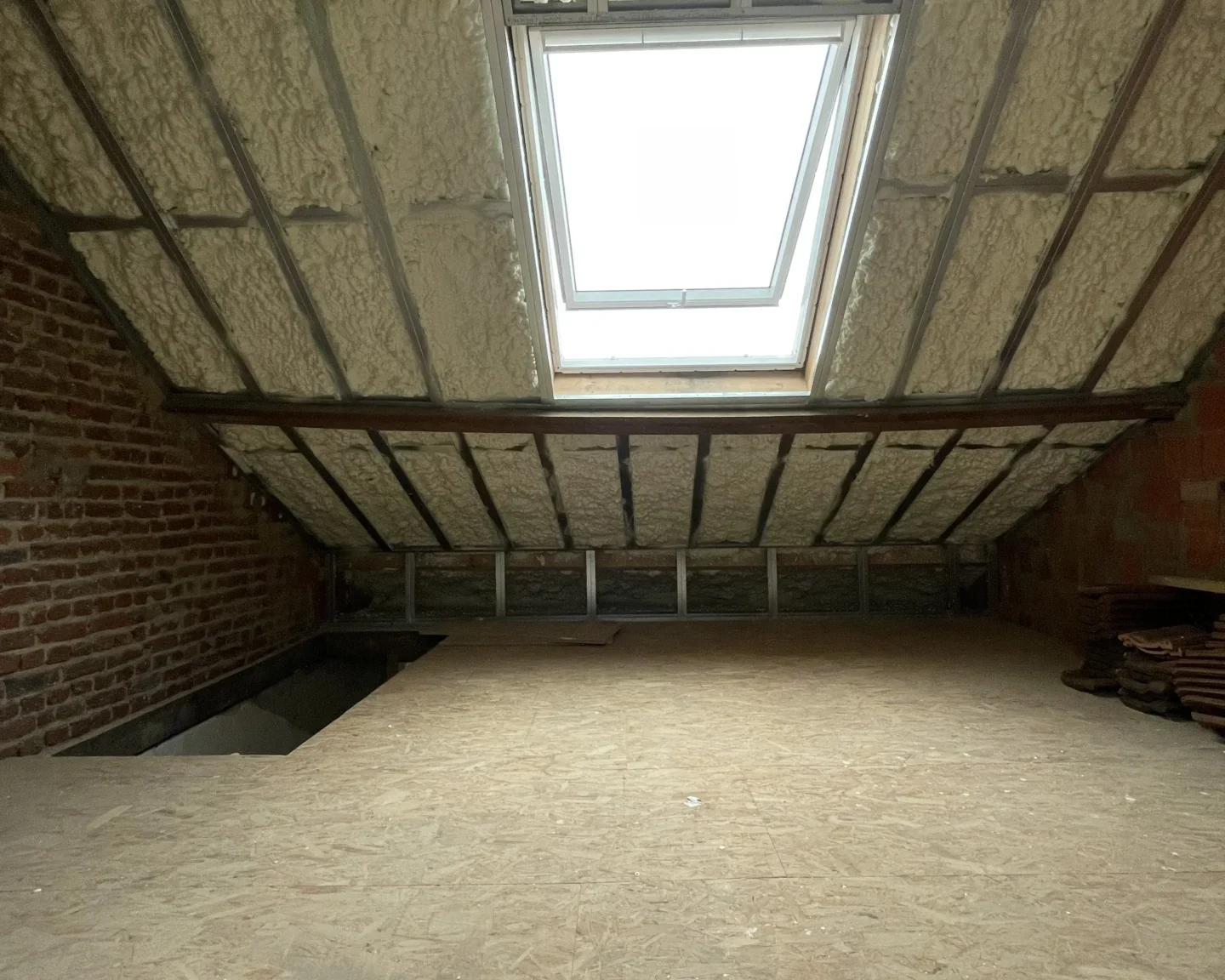 Toiture isolée avec mousse à cellules ouvertes, montrant une finition autour d'une fenêtre de toit pour une isolation thermique optimale à Tilly.