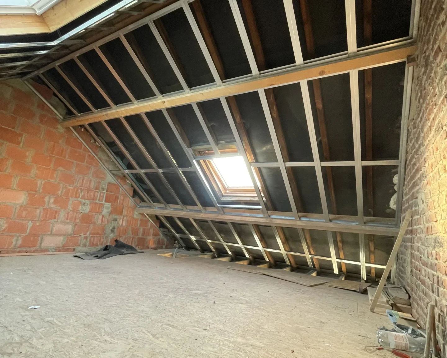 Préparation de la toiture avant l'application de l'isolation avec mousse à cellules ouvertes, mettant en évidence la structure métallique et les ouvertures pour fenêtres de toit à Tilly.