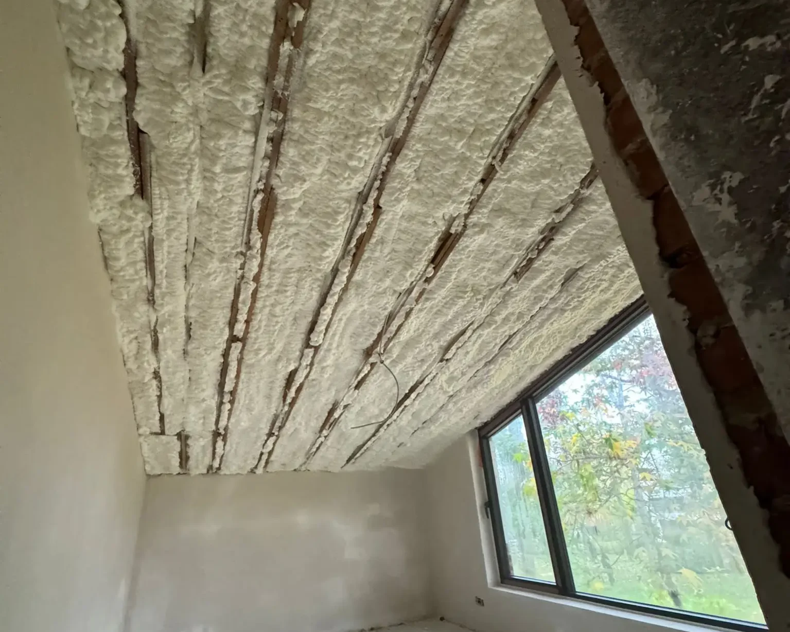 Isolation d'un toit incliné avec de la mousse à cellules ouvertes ICYNENE LITE+ dans une maison en rénovation à Herent, offrant une performance thermique optimale.