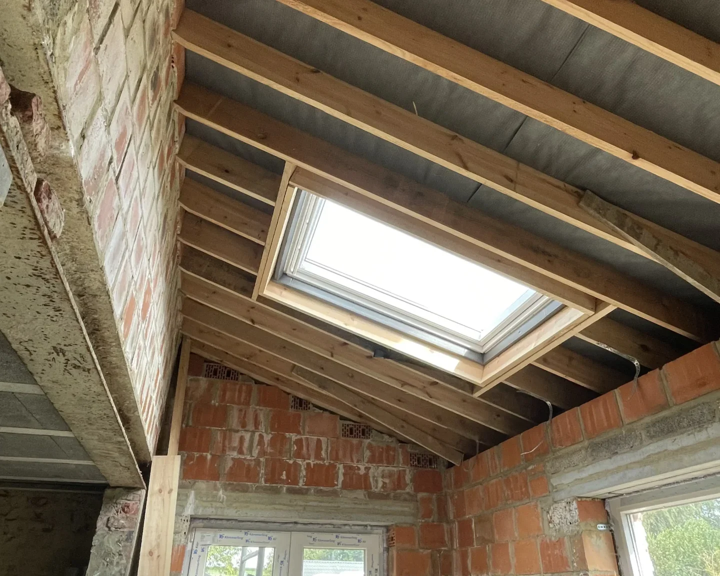 Vue intérieure d'une toiture en cours de rénovation avec une fenêtre de toit installée, illustrant les travaux de préparation avant l'isolation à Tilly.