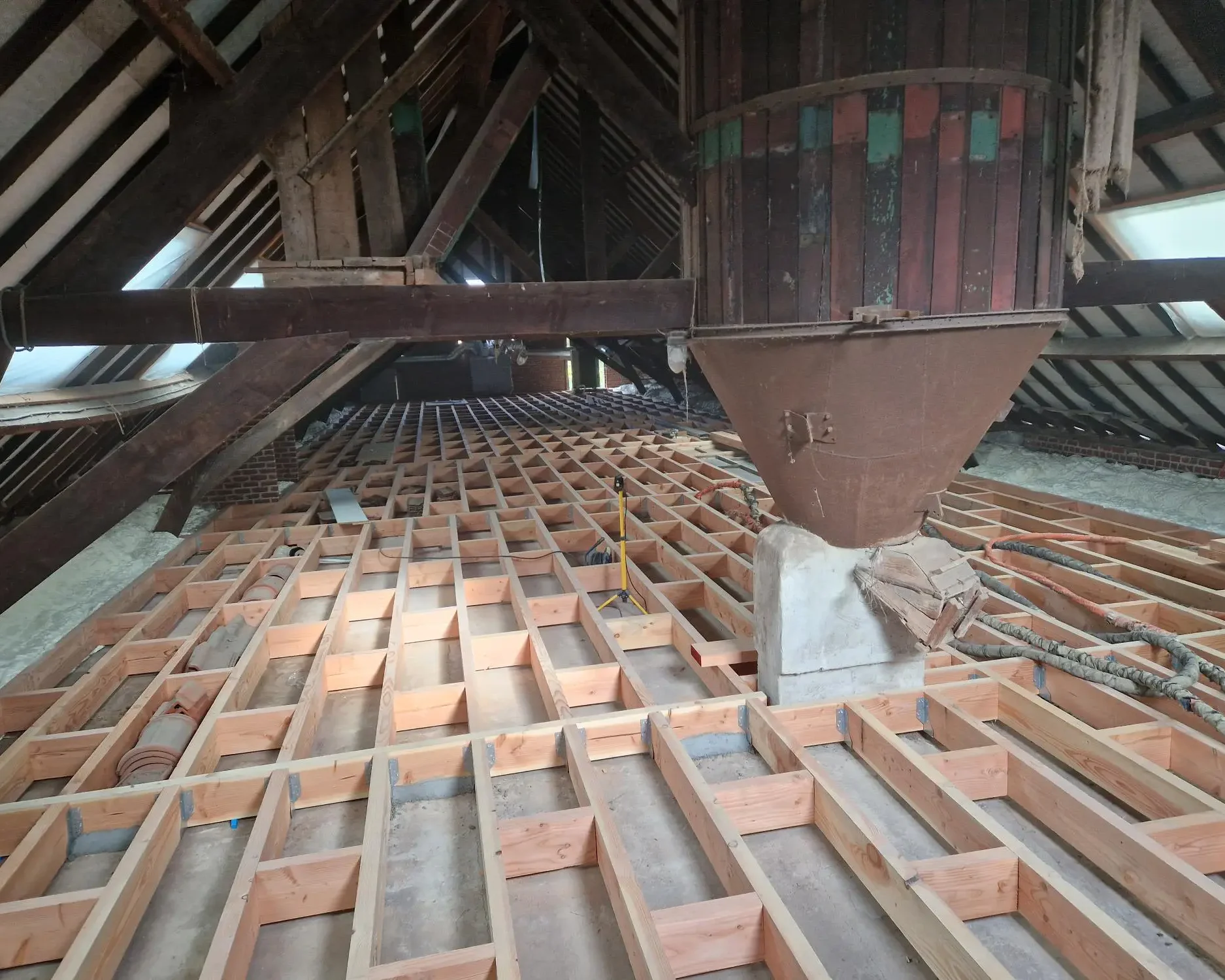 Plancher de grenier à Destelbergen préparé avec un cadre en poutres de bois avant l'application de mousse ICYNENE LITE+ pour une isolation thermique et acoustique optimale.