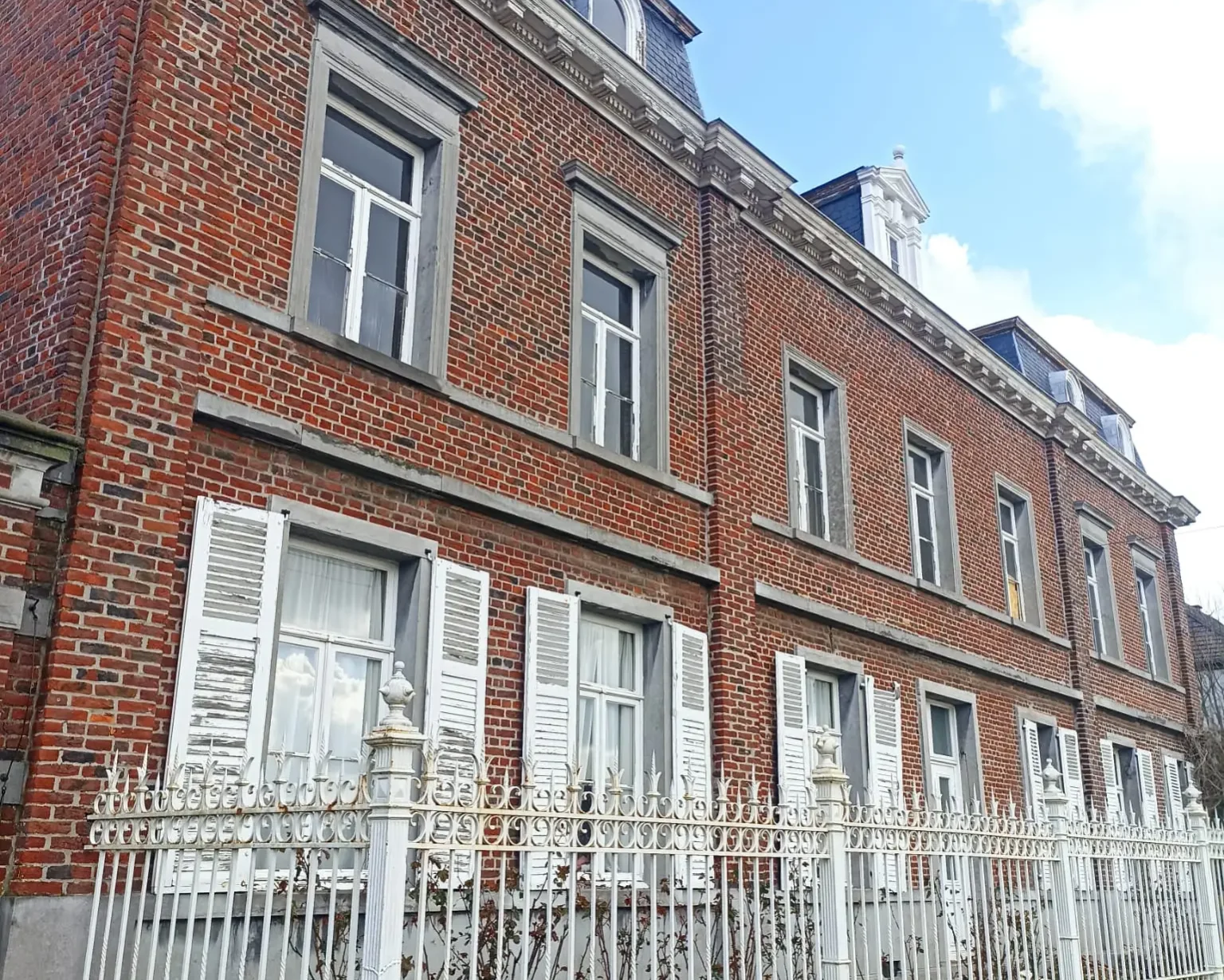 Façade extérieure en briques rouges de la maison de maître à Boussu, rénovée avec une isolation thermique de la toiture pour une meilleure efficacité énergétique.