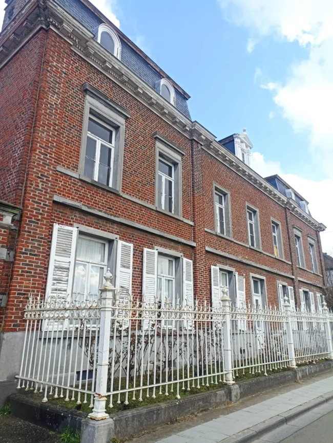 Façade extérieure en briques rouges de la maison de maître à Boussu, rénovée avec une isolation thermique de la toiture pour une meilleure efficacité énergétique.