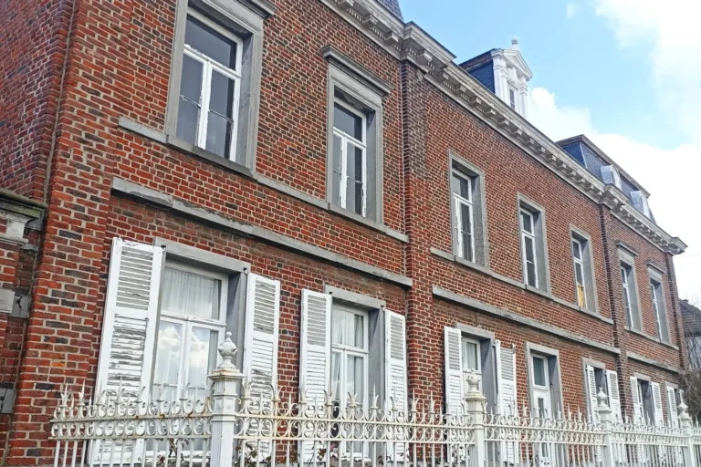 Façade extérieure en briques rouges de la maison de maître à Boussu, rénovée avec une isolation thermique de la toiture pour une meilleure efficacité énergétique.