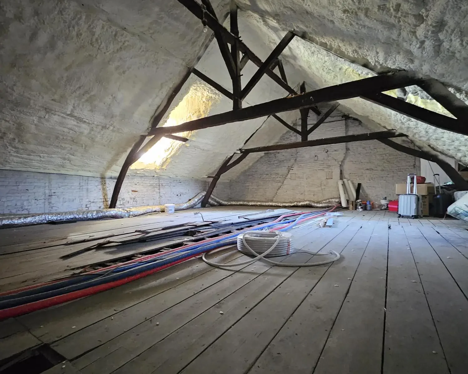 Combles isolés d'une maison de maître à Boussu avec 18 cm de mousse H2O projetée, assurant une isolation thermique optimale et préservant la structure d'époque.