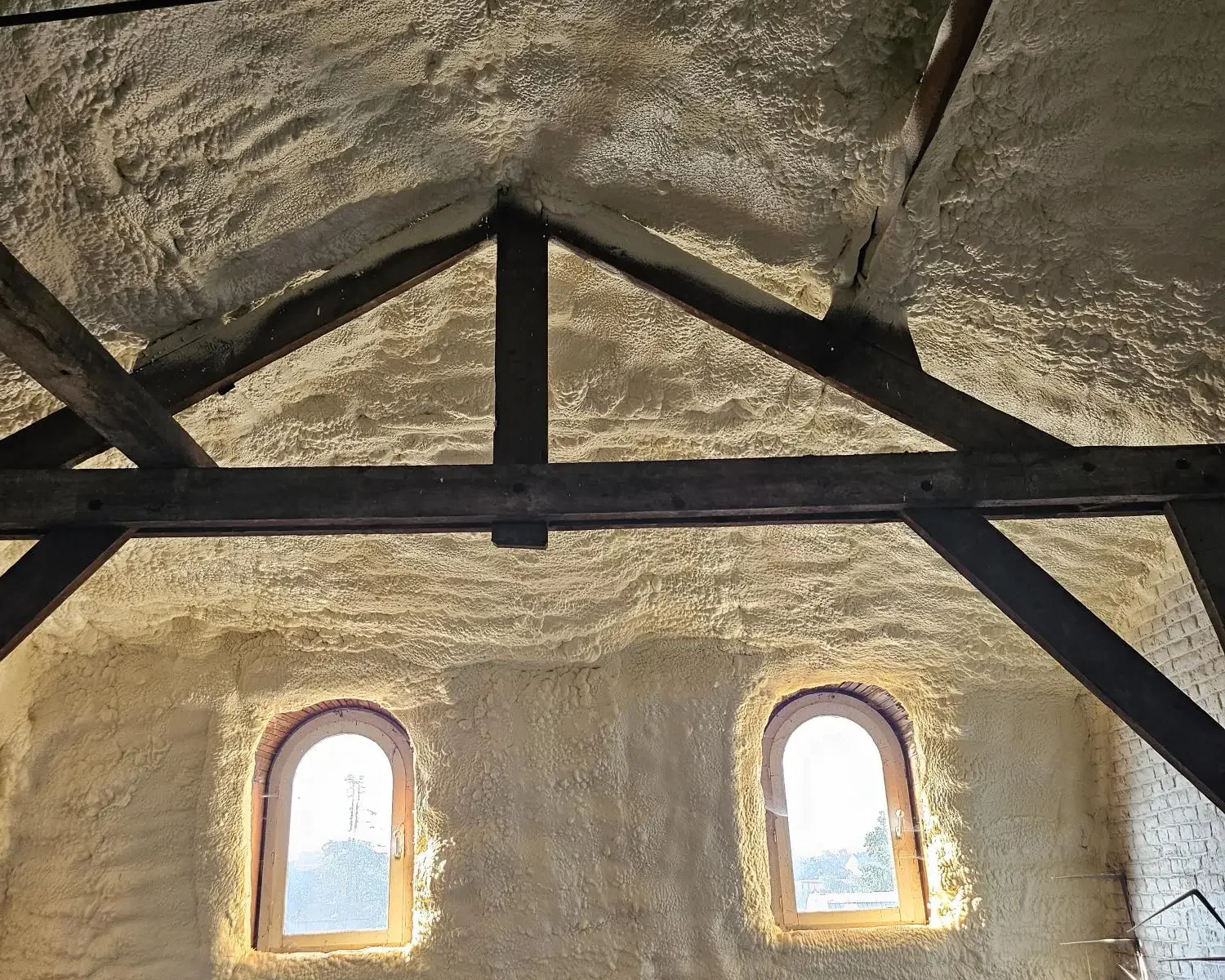 Isolation thermique de la toiture d'une maison de maître à Boussu avec mousse H2O projetée, conservant les poutres apparentes et les fenêtres d'époque.