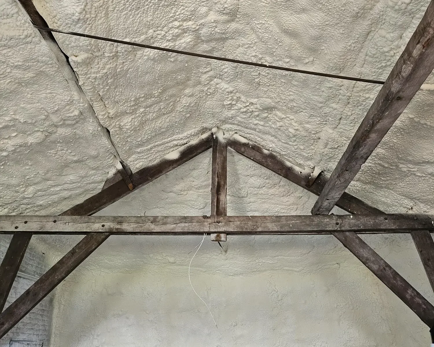 Isolation de la toiture avec mousse projetée H2O dans une maison de maître à Boussu, assurant étanchéité thermique tout en mettant en valeur la charpente bois d'origine.