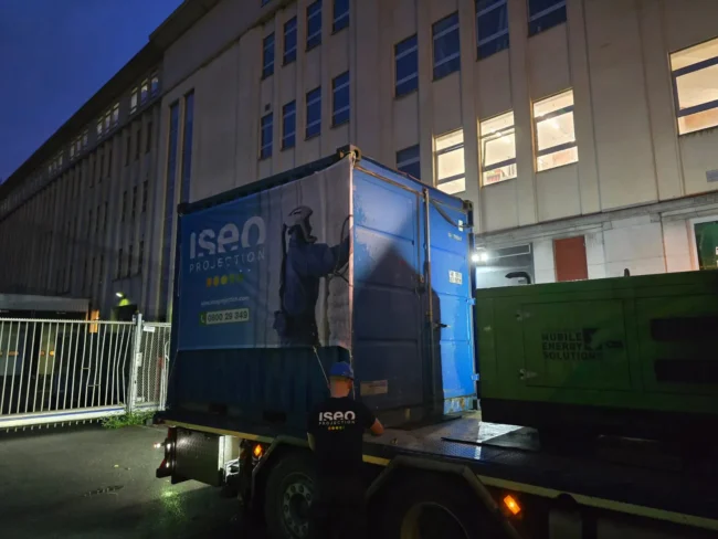Déchargement de l’unité de projection ISEO dans un conteneur pour le chantier d’isolation de la toiture à Forest, en raison des contraintes d’accès au bâtiment.
