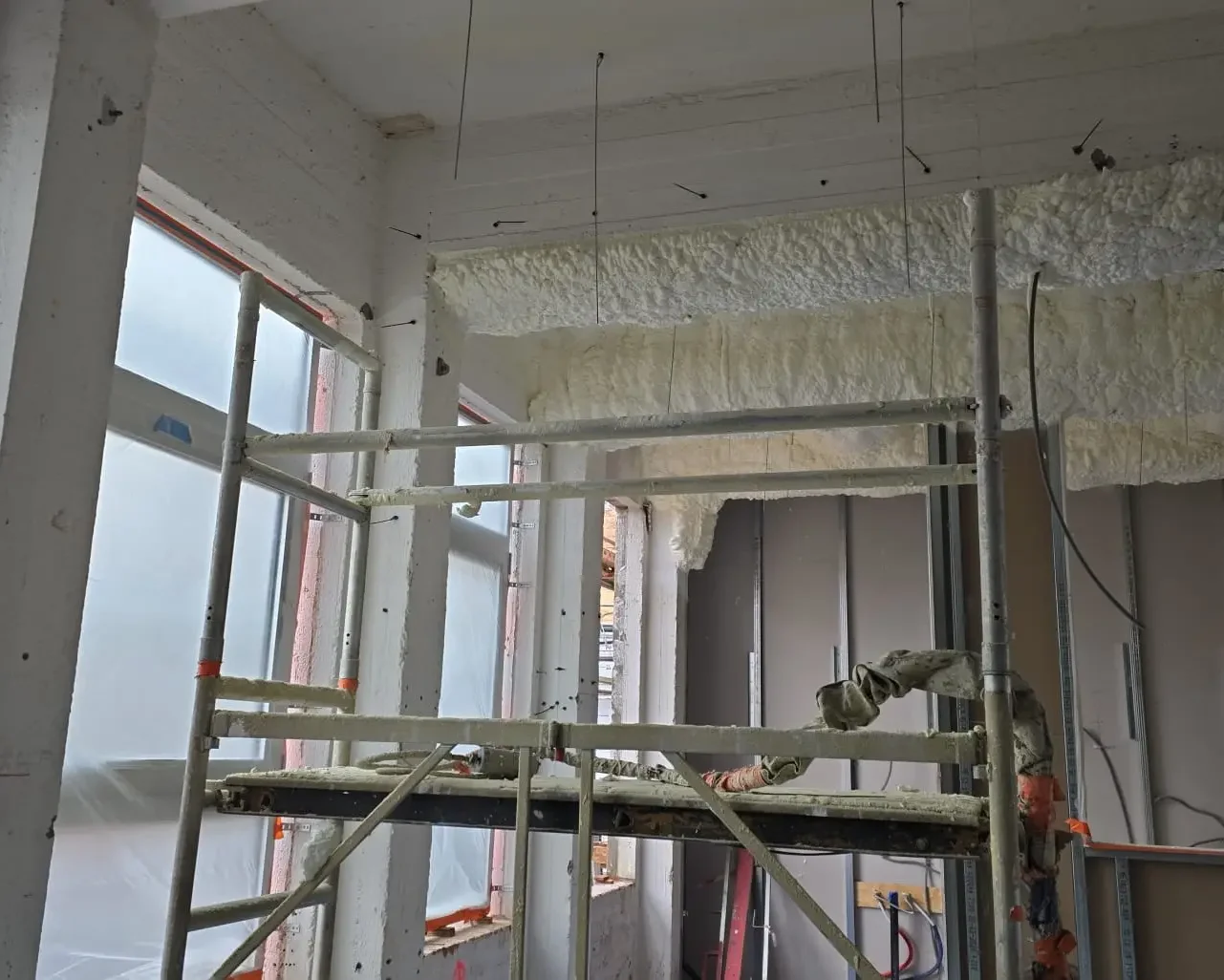 Chantier d’isolation intérieure avec projection de mousse sur plafond et échafaudage en place, réalisé par ISEO Projection à Forest.