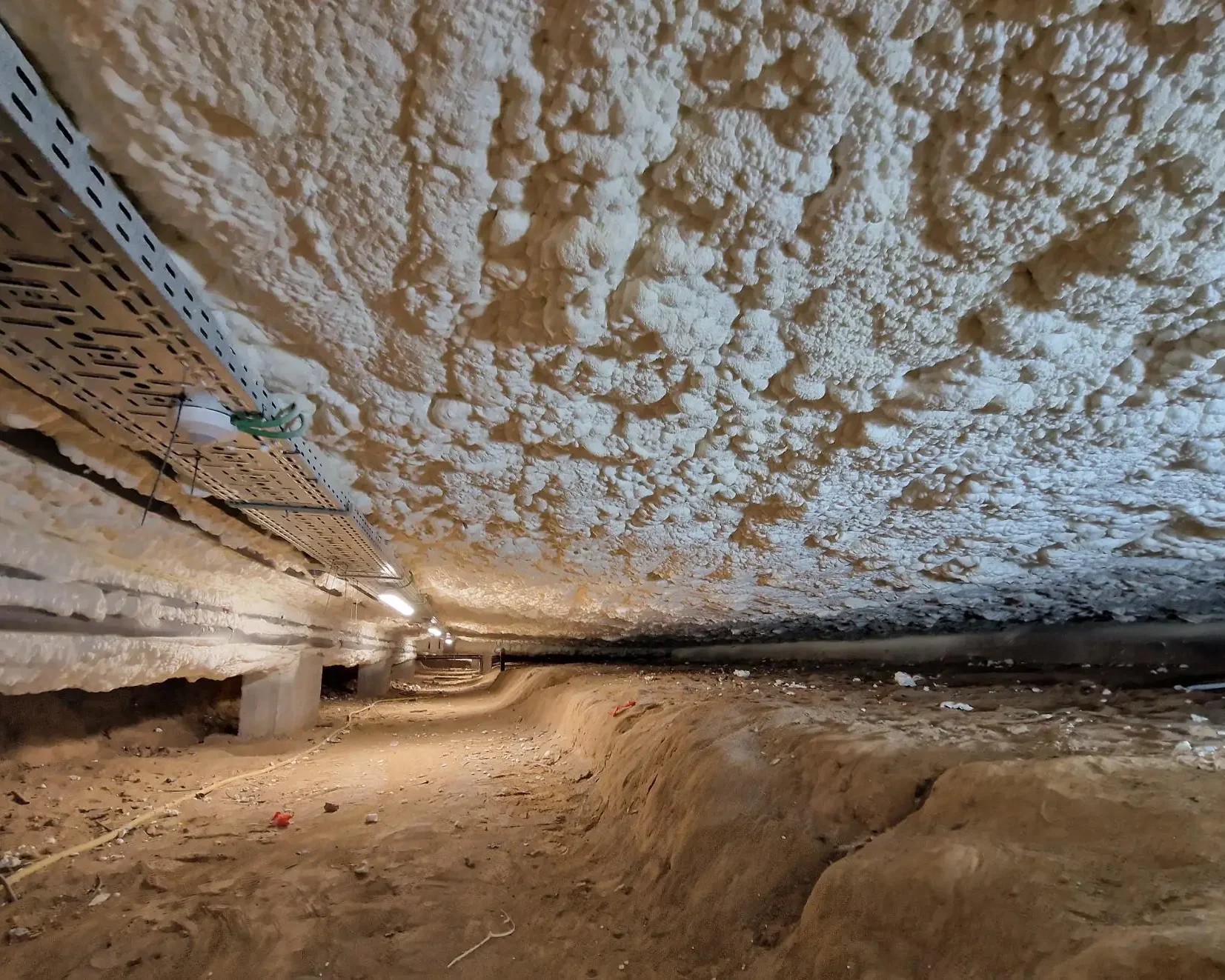 Isolation du vide sanitaire de l'hôtel de ville de Sint-Pieters-Leeuw avec mousse ICYNENE LITE+. Vue du plafond isolé montrant la mousse projetée pour une étanchéité parfaite.