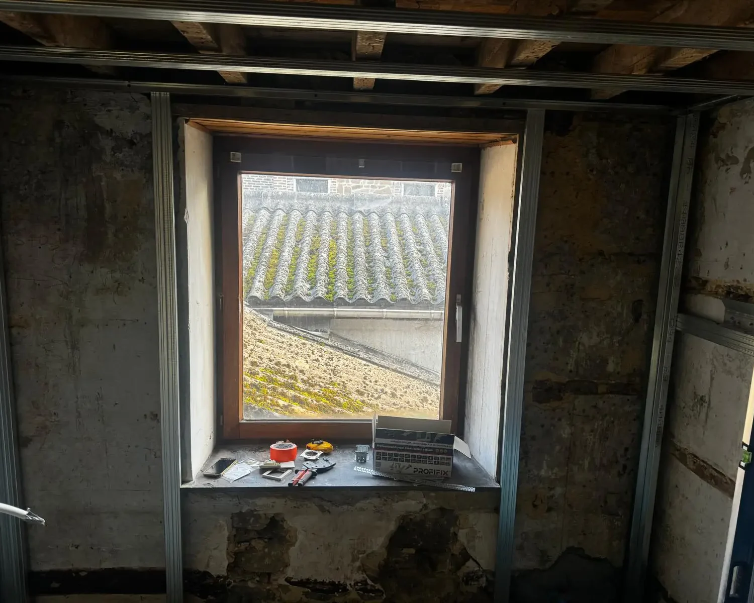Vue intérieure d’une fenêtre en cours de rénovation avec préparation pour isolation et parachèvement à Seilles.