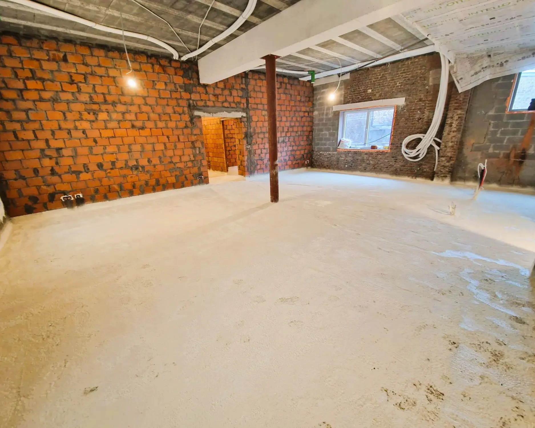 Isolation du sol avec mousse projetée dans un bâtiment en rénovation à Schaerbeek.