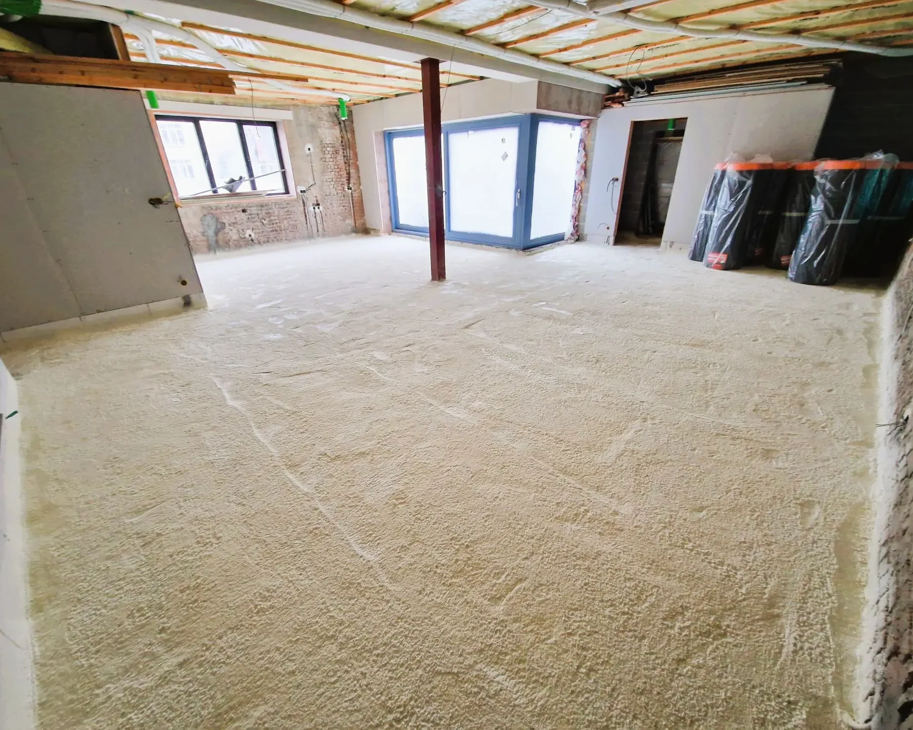 Isolation du sol avec mousse projetée dans un bâtiment en rénovation à Schaerbeek, assurant performance thermique et étanchéité.