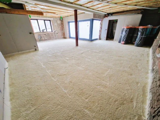 Isolation du sol avec mousse projetée dans un bâtiment en rénovation à Schaerbeek, assurant performance thermique et étanchéité.