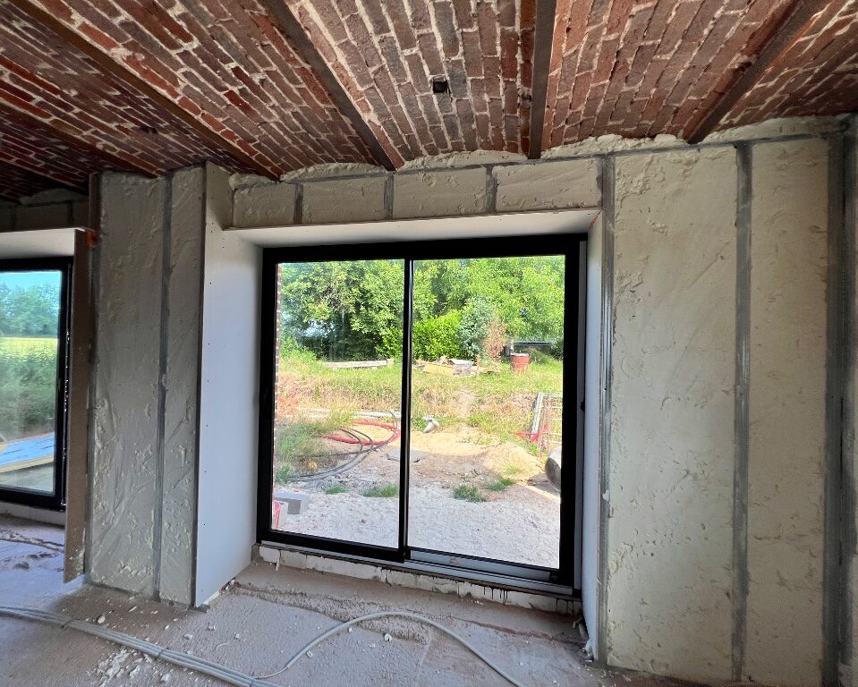 Murs recouverts d'isolant avec des baies vitrées et des voussettes en brique