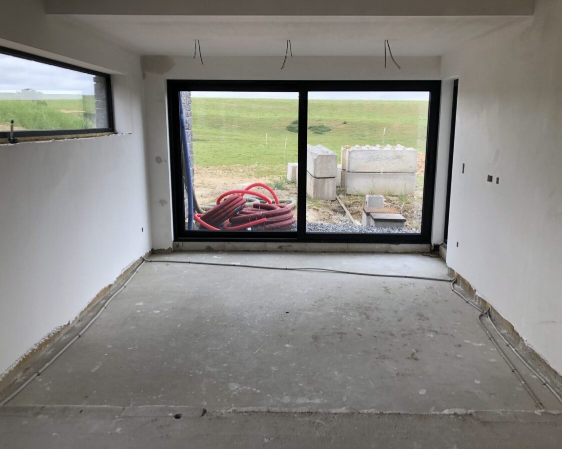Futur salon avec baie vitrée d'une maison neuve à Braibant