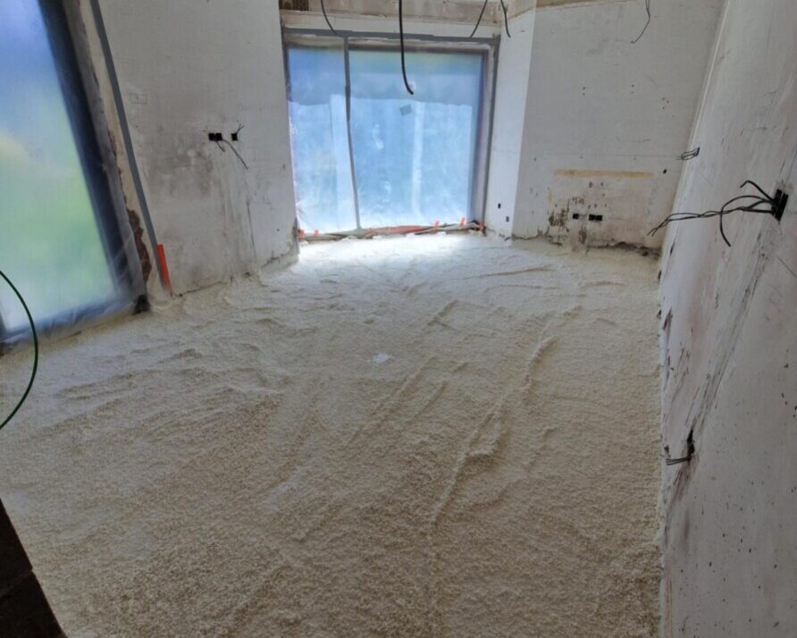 Sol recouvert de mousse projetée avec des murs blancs et des baies vitrées