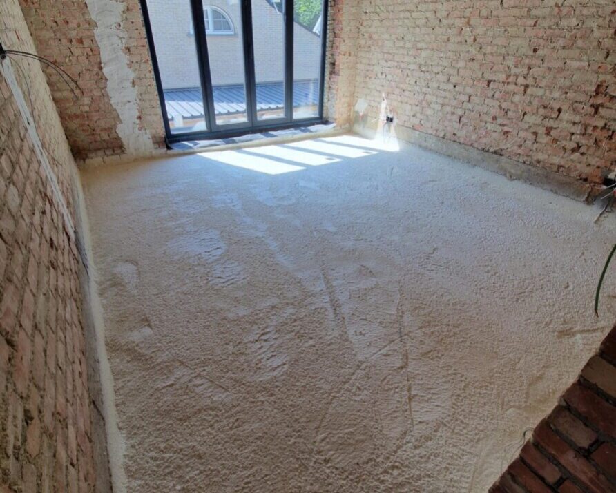 Intérieur d'une maison avec des murs en brique et le sol recouvert de mousse isolante