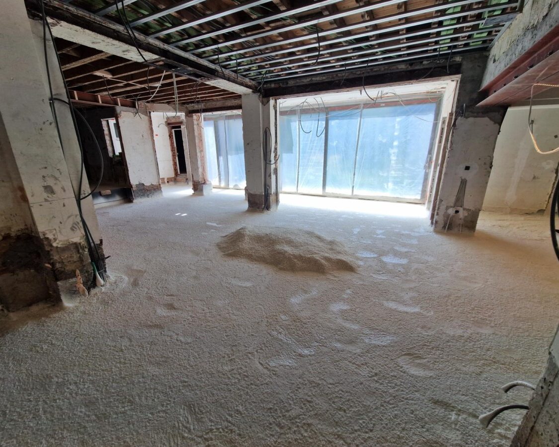 Vue d'un salon en travaux avec le sol recouvert d'isolant par mousse projetée