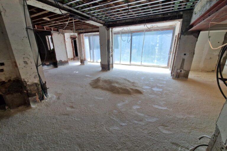 Vue d'un salon en travaux avec le sol recouvert d'isolant par mousse projetée