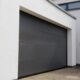 Garage d'une maison moderne en crépi blanc avec une porte sectionnelle gris foncé