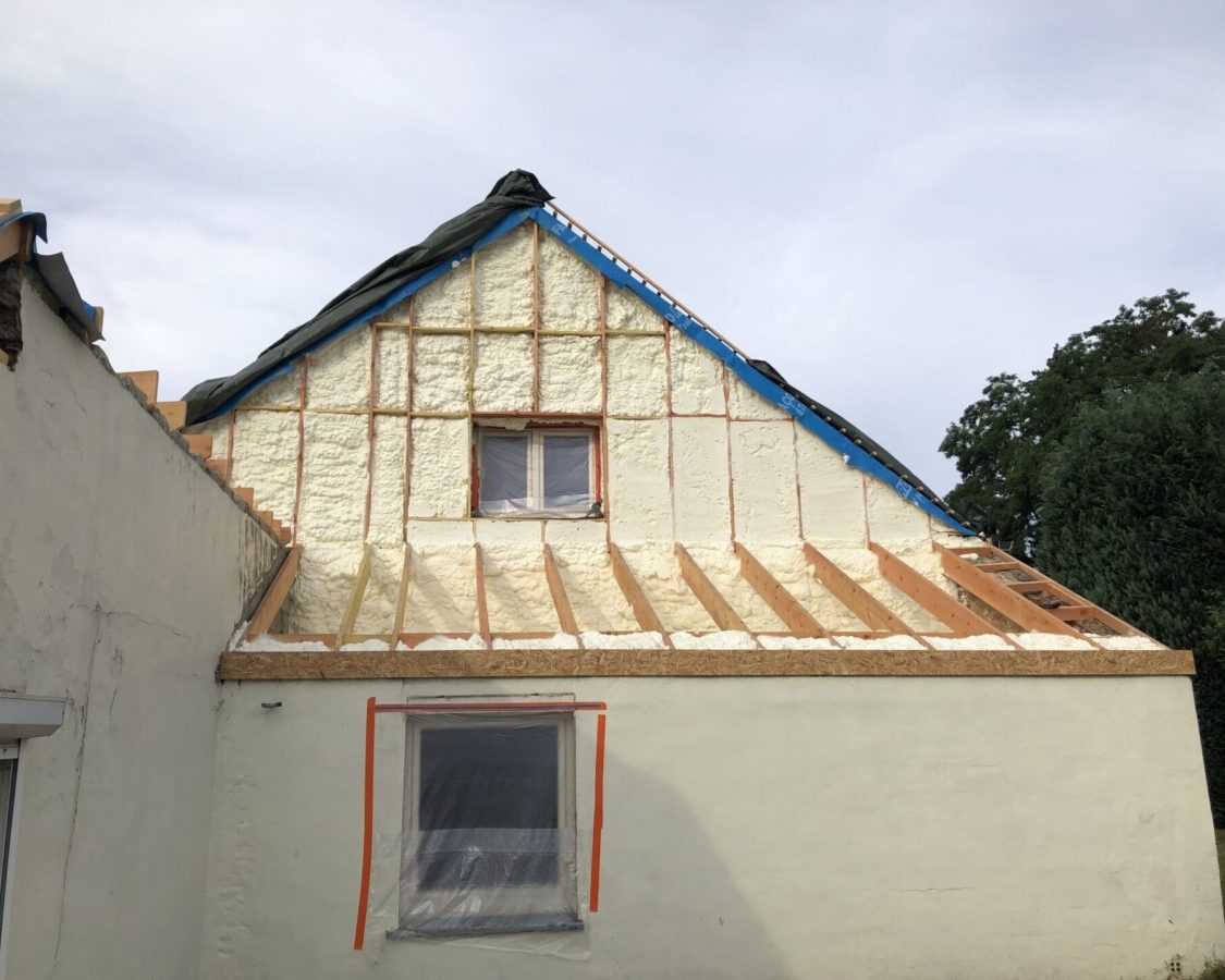 Pignon extérieur d'une maison blanche à Cortil-Wodon que l'on isole avec de la mousse projetée