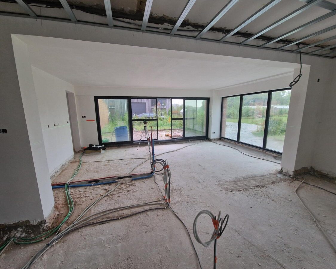 Chantier d'une nouvelle construction avec vue sur le salon et ses baies vitrées