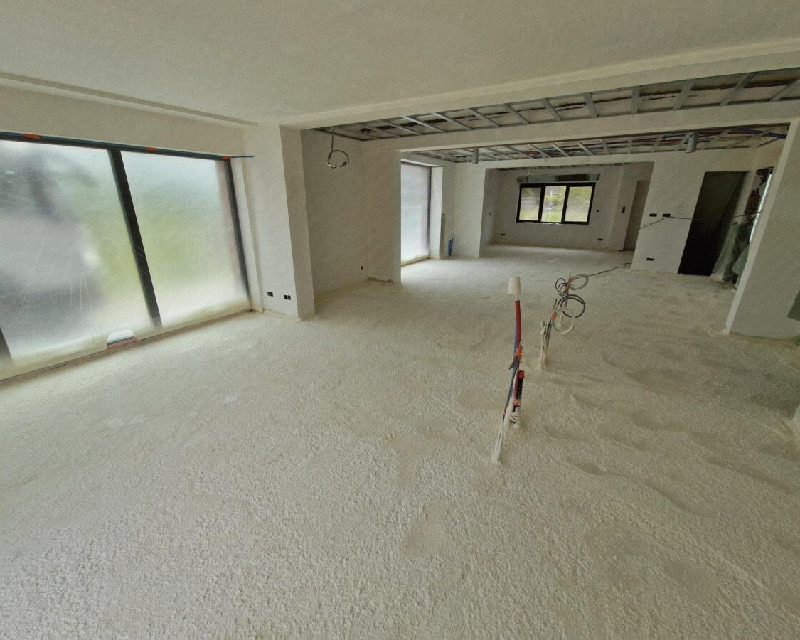 Living d'une maison neuve dont le sol est recouvert de mousse isolante projetée