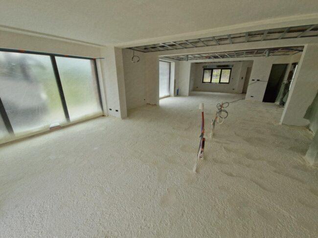 Living d'une maison neuve dont le sol est recouvert de mousse isolante projetée