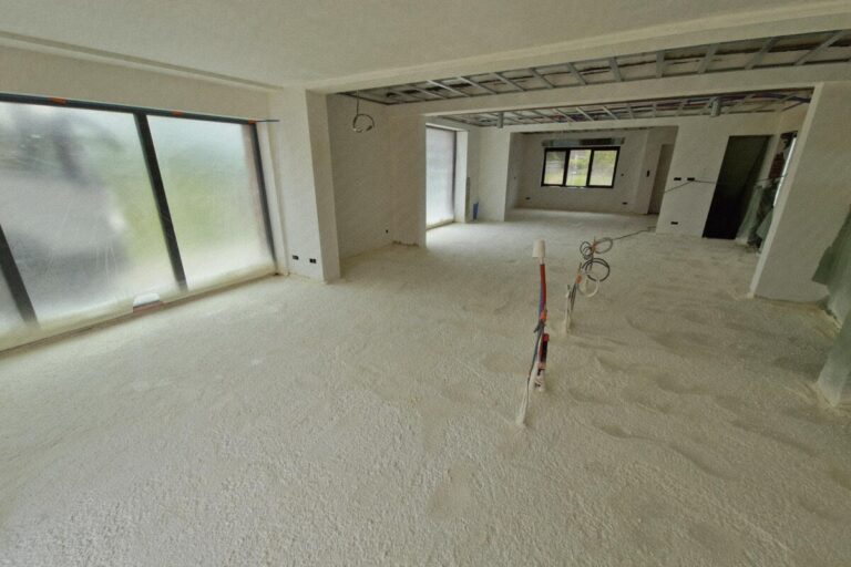 Living d'une maison neuve dont le sol est recouvert de mousse isolante projetée