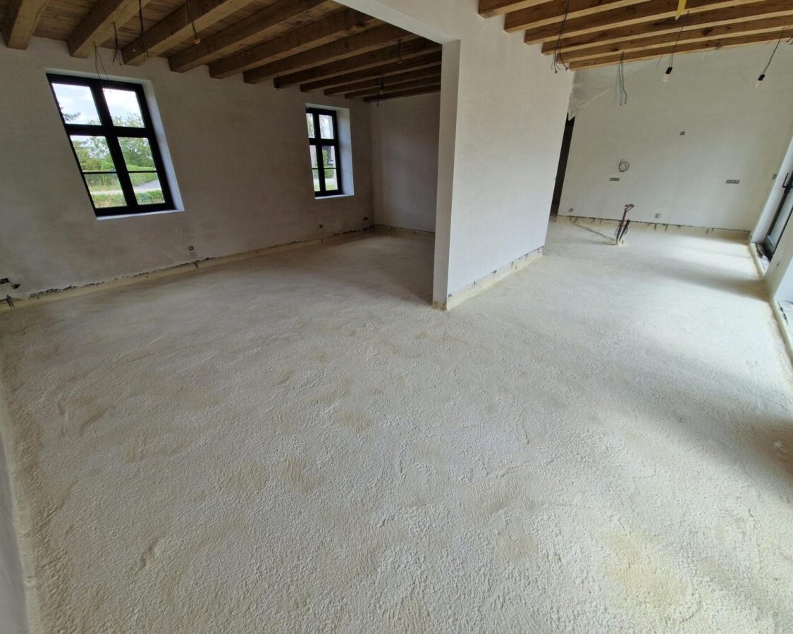 Intérieur d'une ferme en cours de rénovation avec le sol isolé de mousse projetée